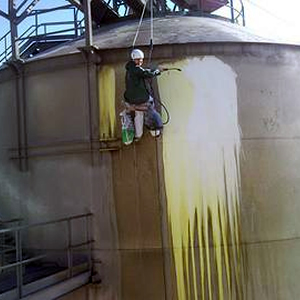 Operario limpiando el exterior de un tanque